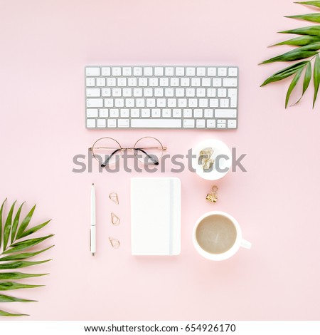 Office table desk with computer,  green leaves palm, clipboard. Magazines, social media. Top view. Flat lay. Home office workspace. Women\'s fashion accessories isolated on pink background.