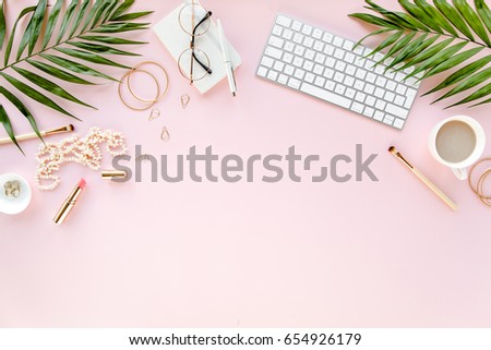 Office table desk with computer,  green leaves palm, clipboard. Magazines, social media. Top view. Flat lay. Home office workspace. Women\'s fashion accessories isolated on pink background.