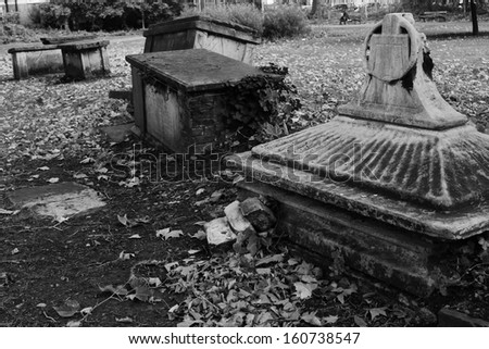 Creepy old derelict overgrown graveyard with tombs sunk and broken graves