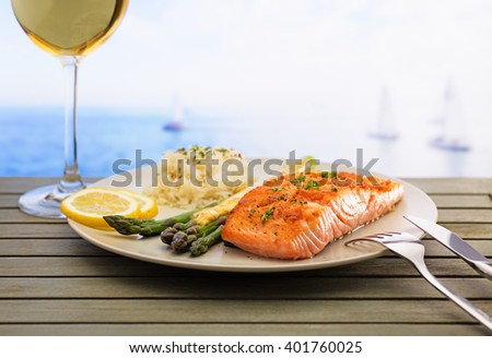 Salmon with asparagus and rice. Freshly served with a glass of wine and sea view .