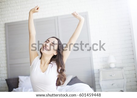 Beatiful brunette Woman stretching in bed after wake up.