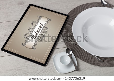 Tablet with stylish restaurant logo and laid table