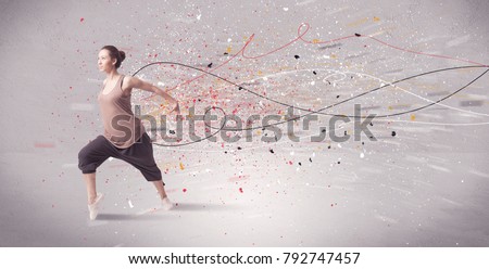 A young contemporary energetic dancer in action in front of a grey wall background with lines, spray dots and splatter concept