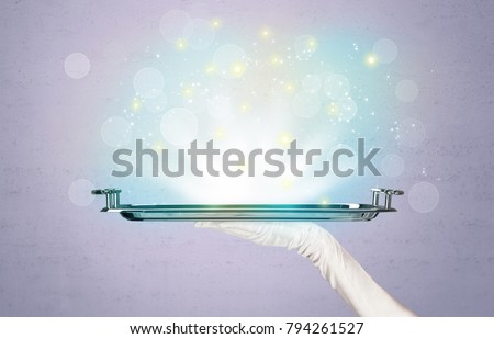 Glowing lights glitter on silver plate served on tray by waiter hand in white elegant glove in front of purple background