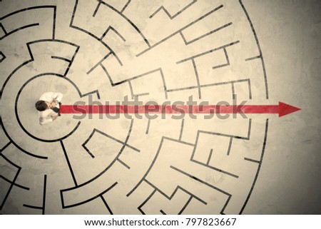 Business person standing in the middle of a circular maze with red arrow