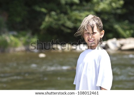 Cute little boy in father\'s shirt by the river