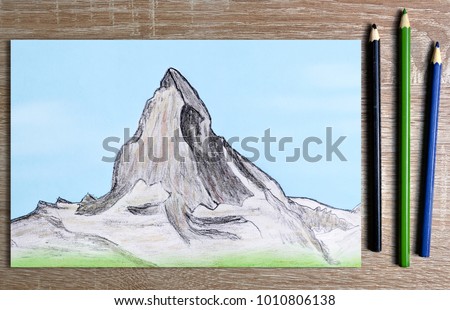 Hand drawn of mountain Matterhorn on paper and pencils on table.