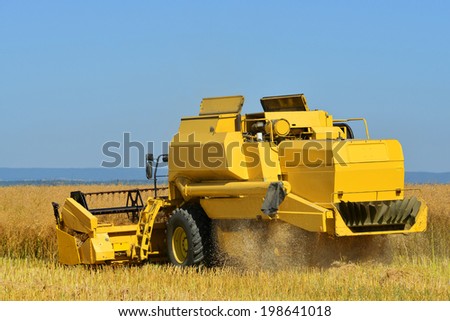 CHLUMCANY, CZECH REPUBLIC - AUG 2, 2013 Combine harvester on a rapeseed field.