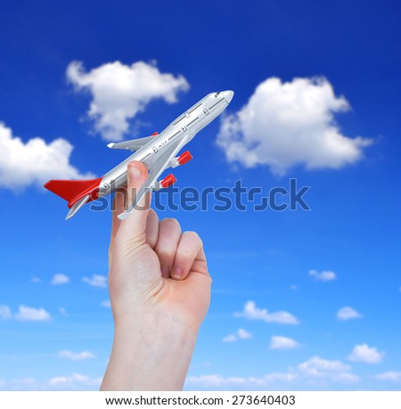 Hand holding the toy plane against cloudy sky