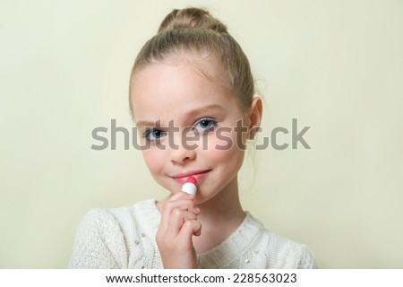 Fashion little girl applying make up. Lip gloss, lipstick.