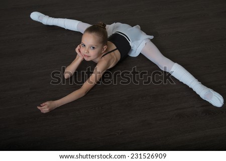 A little adorable young girl doing stretching exercises on the floor. Ballet,  gymnastics, free callisthenics.