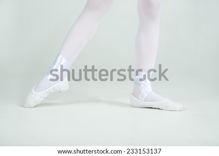Ballerina\'s legs in ballet shoes of young ballerina poses on camera.