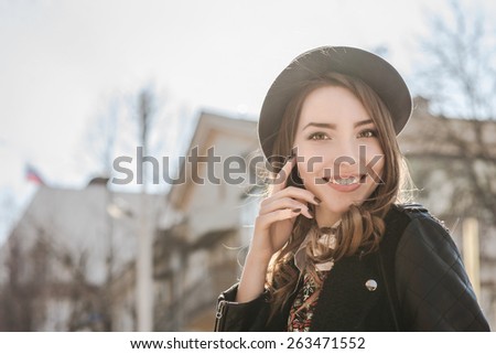 Beautiful brunette girl in casual clothes walking around the city. Fashion and city style. Facial expression. Various flags and the Orthodox Church on background.