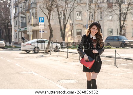 Beautiful brunette girl in stylish dress crosses  the street. Fashion and city style. Facial expression.