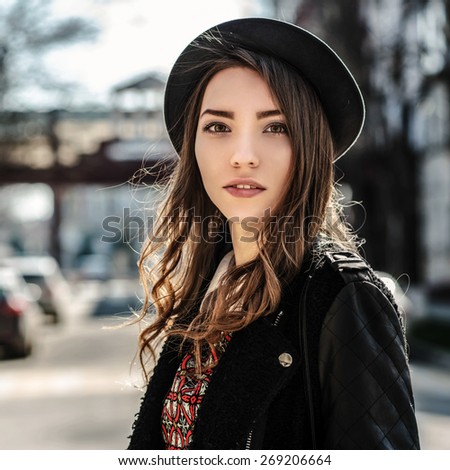 Beautiful brunette girl in casual clothes walking around the city. Fashion and city style. Facial expression.