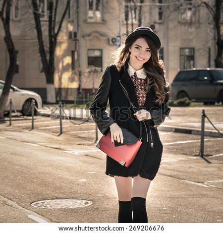 Beautiful brunette girl in stylish dress crosses  the street. Fashion and city style. Facial expression.