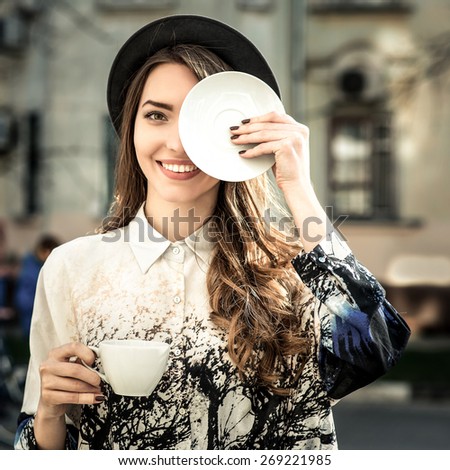 attractive woman poses with white cup. happy smile girl drink smell coffee or tea hold cup, over city background