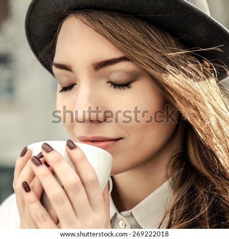 attractive woman poses with white cup. happy smile girl drink smell coffee or tea hold cup, over city background