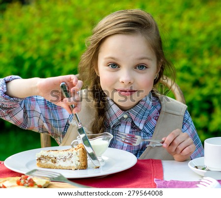 cute smiling little girl sitting by dinner table and eating cake. Kid eats healthy food. Fine dinning.
