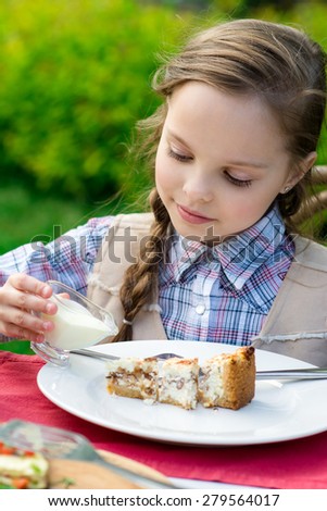 cute smiling little girl sitting by dinner table and eating cake. Kid eats healthy food. Fine dinning.