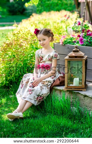 Small girl in colorful dress with flowers in hair. Facial expression.
