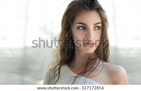 Beauty model with natural nude make up, fresh skin and wet hair s posing front of the window. Youth and Skin Care Concept.  Make up and Hair.  Close up, selected focus.