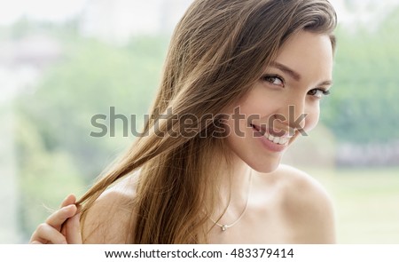Beauty smiling model with natural make up and long eyelashes shows her hair. Hair care concept, Treatment of split or brittle hair. Spa and wellness. Close up, selective focus.