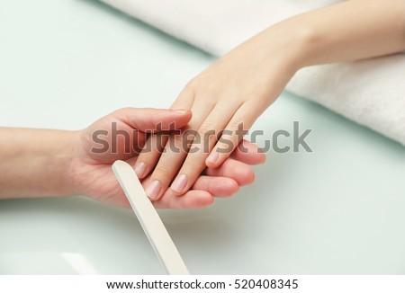 Woman hands in a nail salon receiving a manicure.  Nail filing. Close up, selective focus.