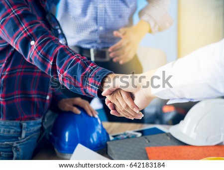 Successful deal, Female architect shaking hands with client in construction site after confirm blueprint for renovate building.