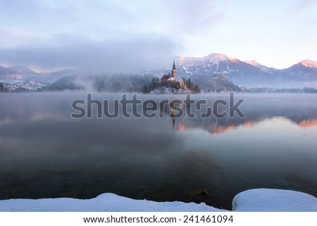Lake Bled in the winter morning: the snowy island with mountains and castle in the background