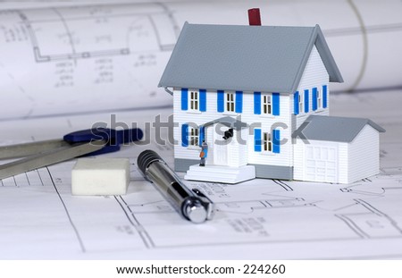 Miniature House With Various Drafting Items and Blue Prints.