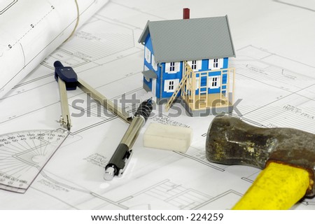 Miniature House With Various Drafting Items and Blue Prints.