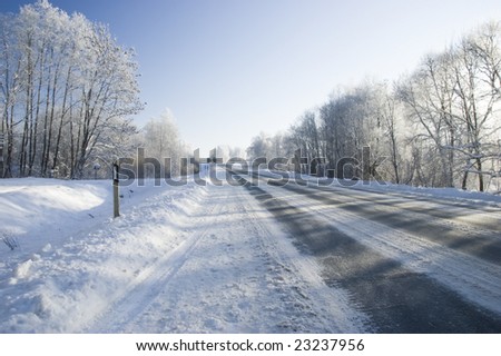 Frozen trees and snowy land road at winter, deep blue sky