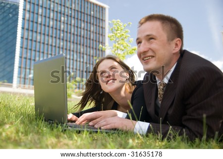 Young happy business team working with laptop outdoor on the grass