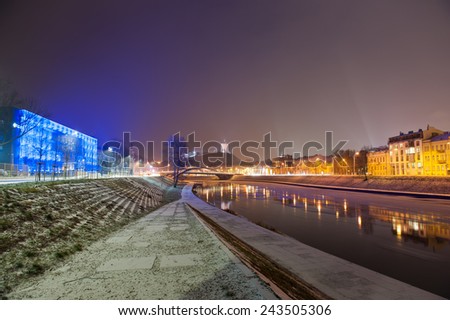 Vilnius city in winter at night - river Neris, Mindaugas bridge, Gediminas tower and old town in front. Lithuania.