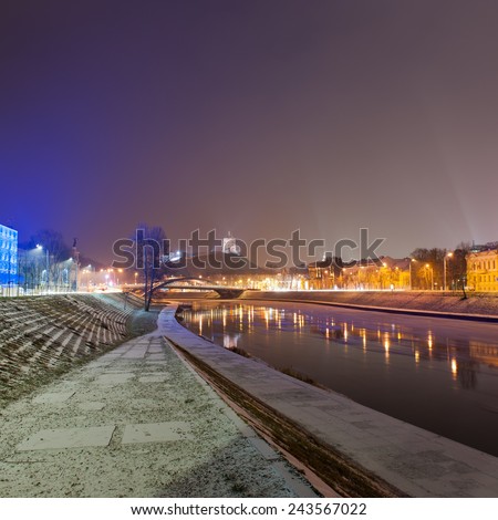 Vilnius city in winter at night - river Neris, Mindaugas bridge, Gediminas tower and old town in front. Lithuania.