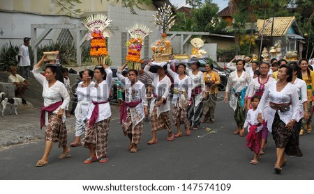 DENPASAR, BALI - MAY 12: A street procession of local village women carrying offerings on their heads for a Ngaben or cremation ceremony in Ubud, Bali, Denpasar, Indonesia on May 12, 2013.