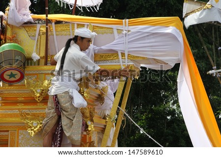 DENPASAR, INDONESIA - MAY 12: A Balinese holy man rides the funeral pyre scaring away evil spirits in a Ngaben or cremation ceremony in Ubud, Denpasar, Bali, Indonesia on May 12, 2013.