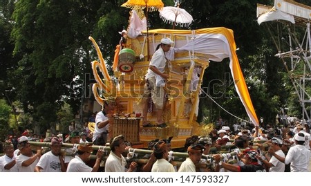 DENPASAR, INDONESIA - MAY 12: A Balinese holy man rides the funeral pyre scaring away evil spirits in a Ngaben or cremation ceremony in Ubud, Denpasar, Bali, Indonesia on May 12, 2013.
