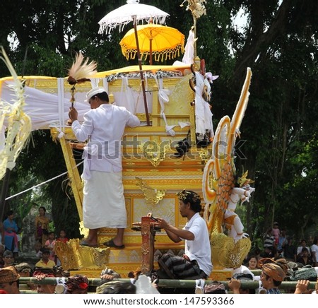 DENPASAR, INDONESIA - MAY 12: Two Balinese holy men ride the funeral pyre scaring away evil spirits in a Ngaben or cremation ceremony in Ubud, Denpasar, Bali, Indonesia on May 12, 2013.