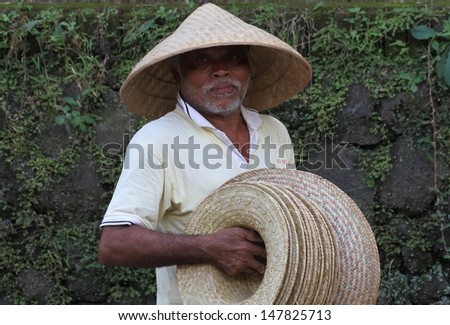 DENPASAR, INDONESIA - MAY 13: Traditional Balinese street vendor selling hats in Ubud\'s main street during a Royal Ngaben or cremation ceremony in Ubud, Denpasar, Bali, Indonesia on May 13, 2013.