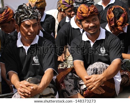 DENPASAR, INDONESIA - MAY 13:  Local Balinese men in traditional dress sitting down at a Royal Ngaben or cremation ceremony in Ubud, Denpasar, Bali, Indonesia on May 13, 2013.