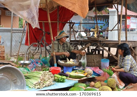 SIEM REAP, CAMBODIA - NOVEMBER 23: A Cambodian woman selling her vegetables to another woman at a local market near Siem Reap, Cambodia on the 23rd November, 2013.