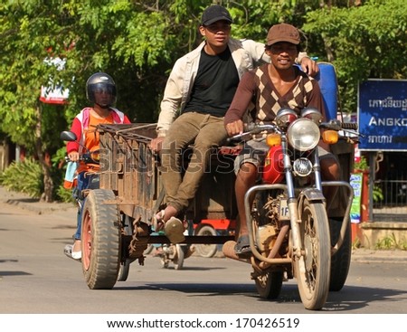 SIEM REAP, CAMBODIA - NOVEMBER 27: A common scene of two Cambodian men on a motor bike with a trailer in Siem Reap, Cambodia on the 27th November, 2013.