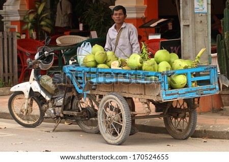 SIEM REAP, CAMBODIA - NOVEMBER 27: A Cambodian street food hawker selling green coconuts from a cart in Siem Reap, Cambodia.