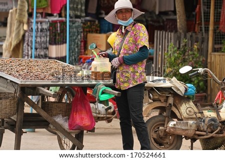 SIEM REAP, CAMBODIA - NOVEMBER 27: A Cambodian street food hawker selling cooked spiced snails from a tray cart in Siem Reap, Cambodia.