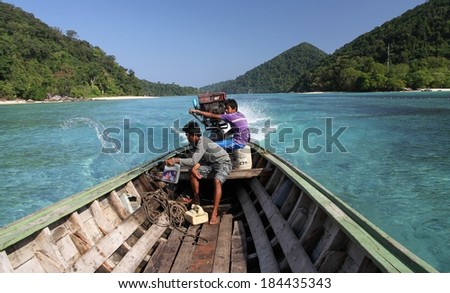 PHANG NGA, THAILAND - MARCH 11: Young male Moken Sea Gypsies driving a motorised long tail boat on the Andaman Sea near Mu Ko Surin National Park, Phang Nga, Thailand on the 11th March, 2014.