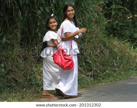 DAMBULLA, SRI LANKA - FEBRUARY 15: Two young Sri Lankan females in traditional school dress walking along the road in a country town near Dambulla, Sri Lanka on the 15th February, 2014.