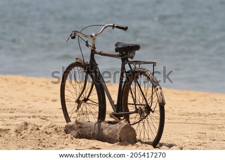 An old bicycle resting against a log on the beach at Negombo, Sri Lanka.