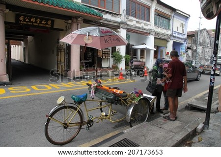 GEORGE TOWN, MALAYSIA - MAY 30: A street scape view of people and a bicycle rickshaw in a street of George Town, Malaysia on the 30th May, 2014.